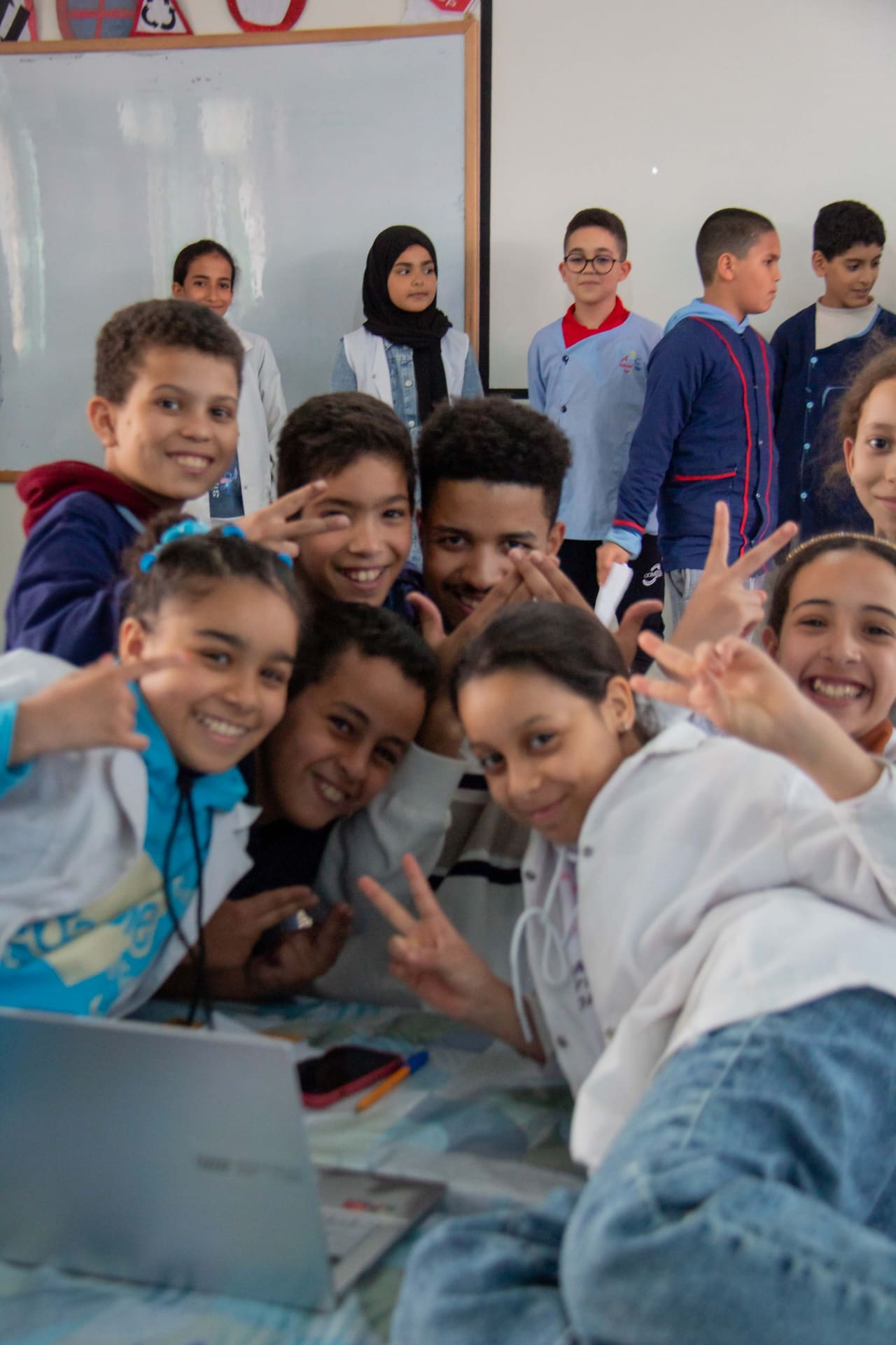 Students making a victory sign around a laptop at the end of their workshop