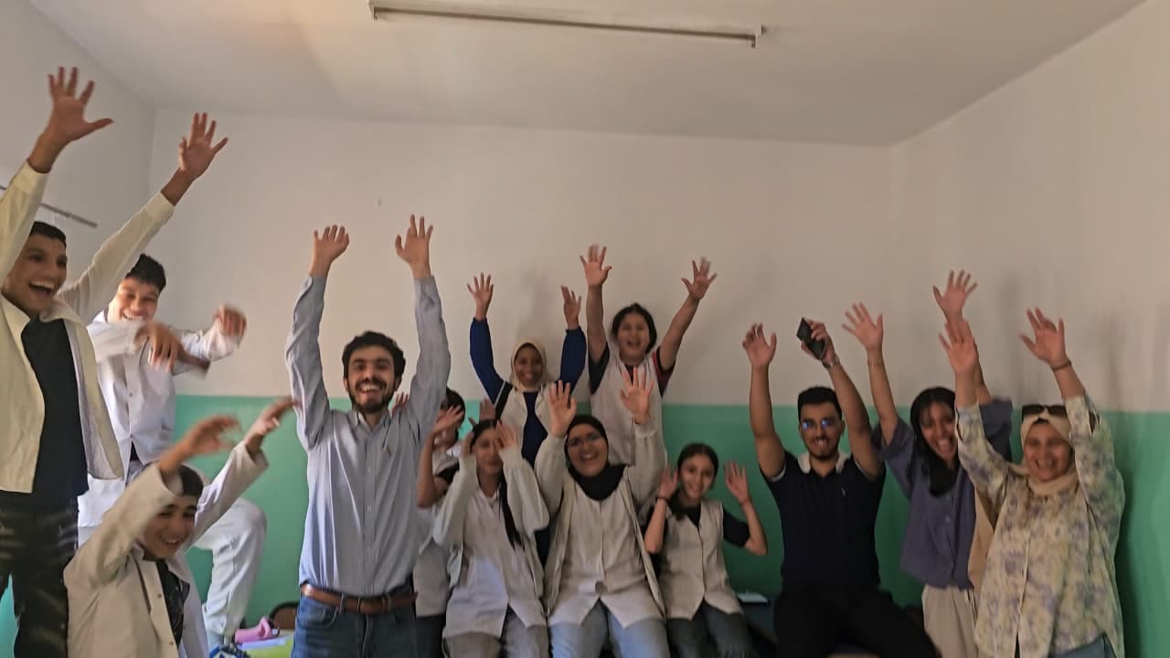 A whole class raising their hands at the end of the hackathon
