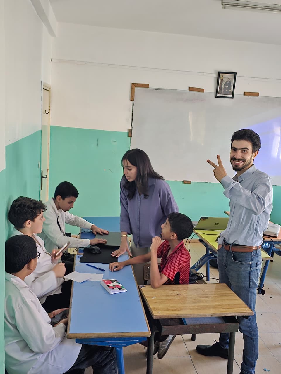 A mentor helping a student team around a laptop
