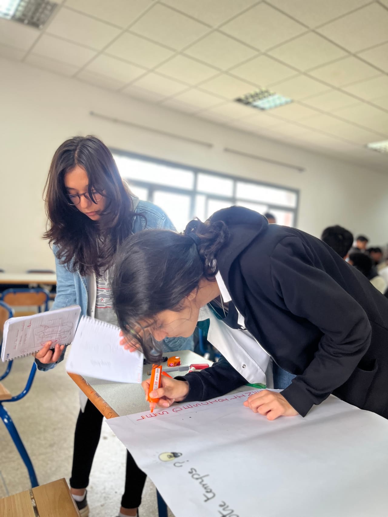 Two students sketching their business model on a large sheet during a TafraTech workshop