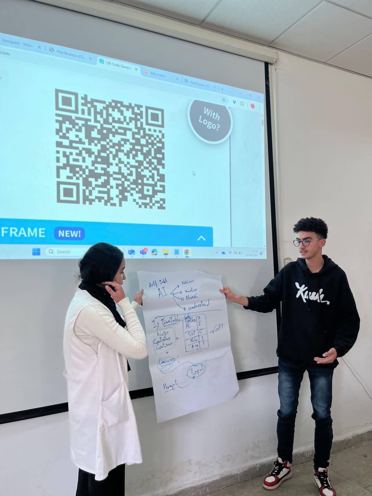 Two students walking through their reasoning on a sheet pinned to the board