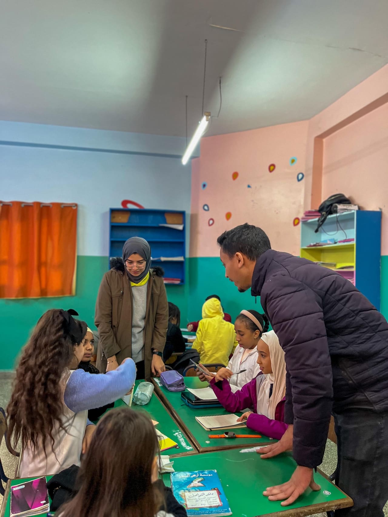 A mentor helping primary pupils at their table